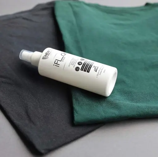 Image of a bottle of iFlat spray on a two-toned background with black and green fabric.