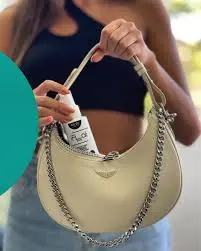 A woman placing a bottle into a stylish crescent-shaped handbag.