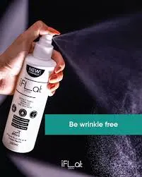 A hand holding a wrinkle-release spray bottle with mist spraying out, featuring "Be wrinkle free".